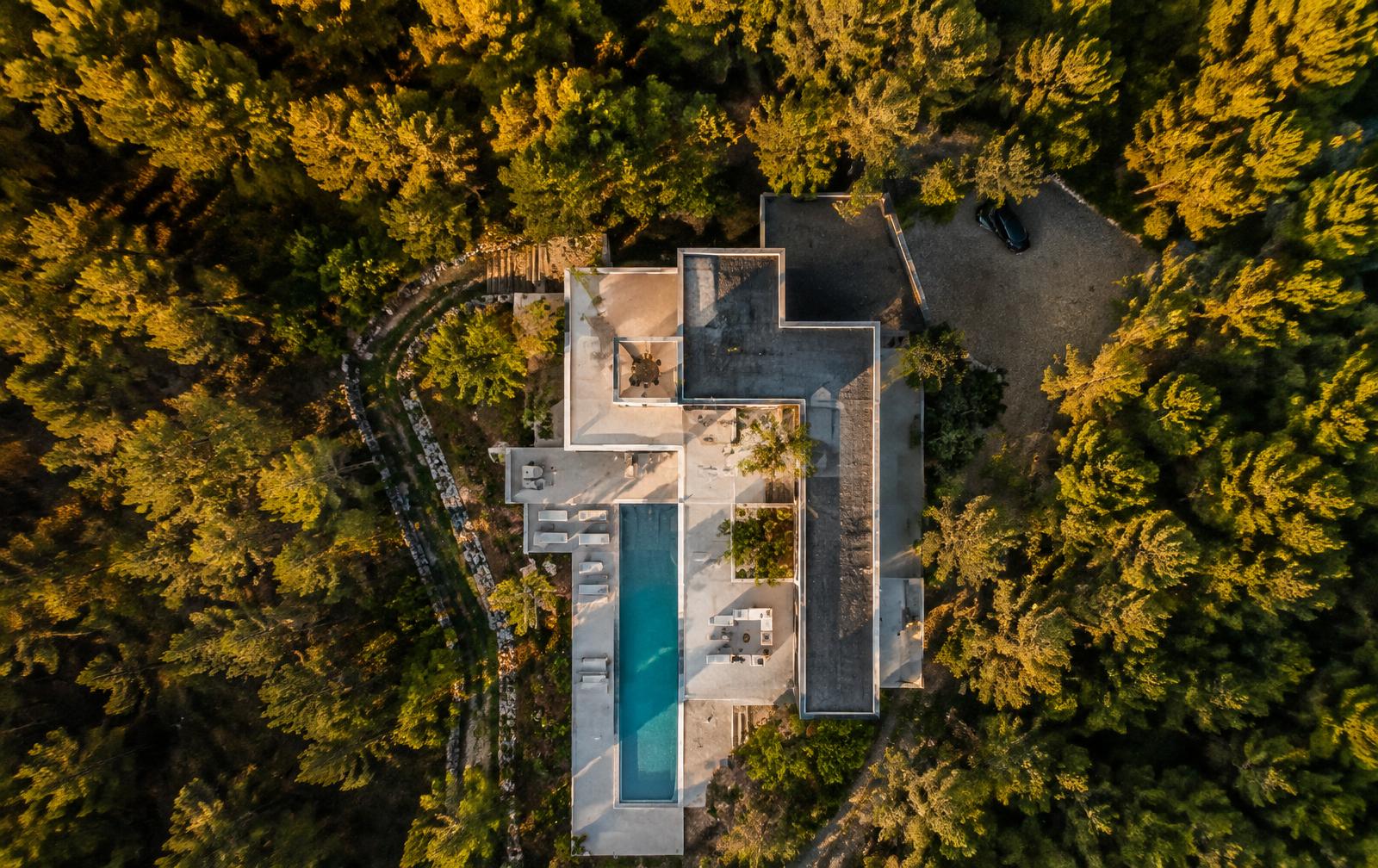 Aerial view of a modern house and pool in pine forest