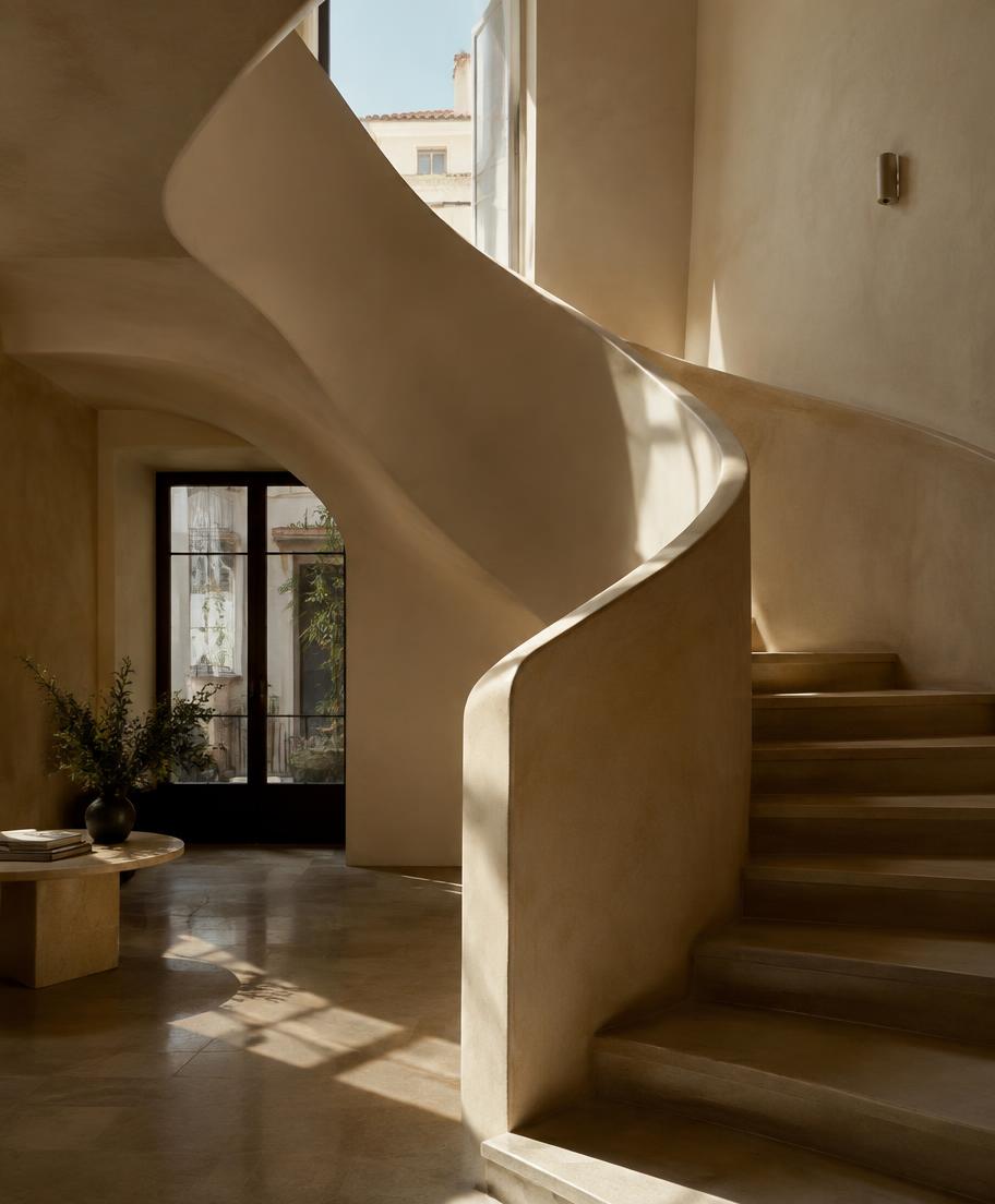 Sculptural staircase in a sunlit atrium at Vera House